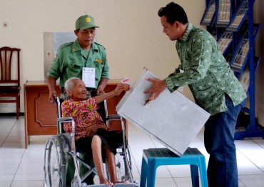 Petugas membantu warga lanjut usia memasukkan surat suara yang telah dicoblos di TPS 3 yang menempati Panti Jompo Wening Wardoyo, Kuncen, Ungaran Barat, Kabupaten Semarang, Jawa Tengah, Rabu (9/12).